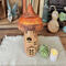 A fairy house mushroom made with a real dried gourd. Windows are carved out of the gourd shell. The top is burnt orange, the bottom is tan.